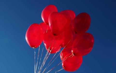 红色的心形气球在天空的Mac壁纸